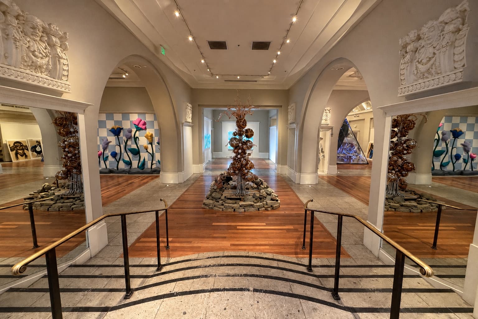 Inside the Coliseum of Art, with arched galleries, glass flowers, warm wood floors, and sculptural light.